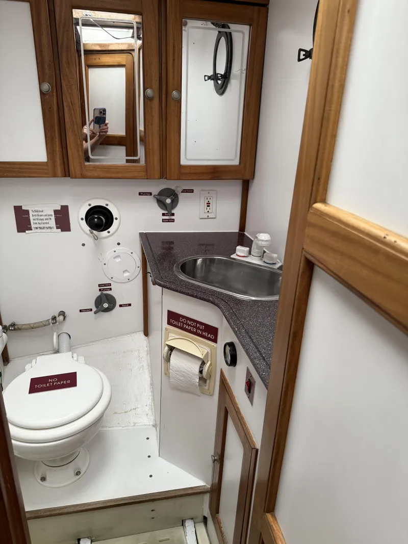 Slide: The Image of 1976 Frers Custom yacht bathroom with wooden cabinets, sink, and marine toilet. - 29