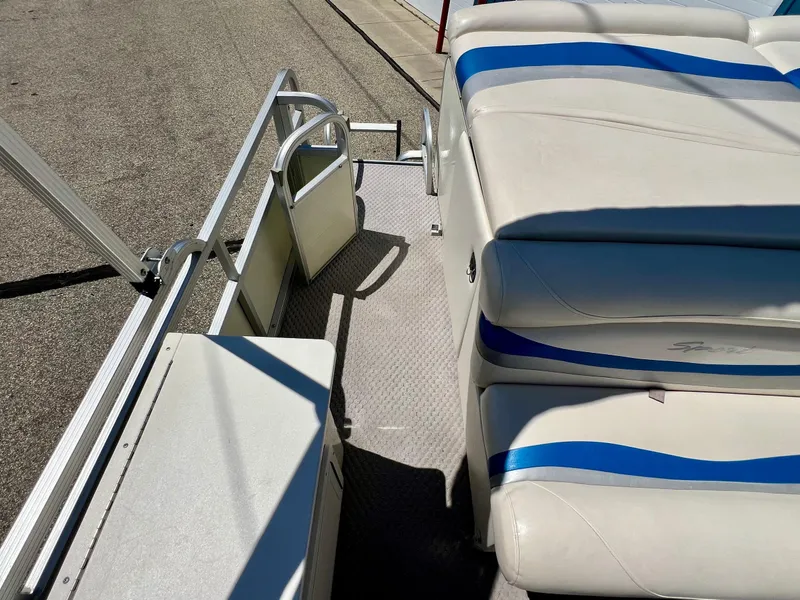 Slide: The Image of 2004 Bennington 2875RLX boat interior with white and blue seating, metal railings, and textured flooring. - 12