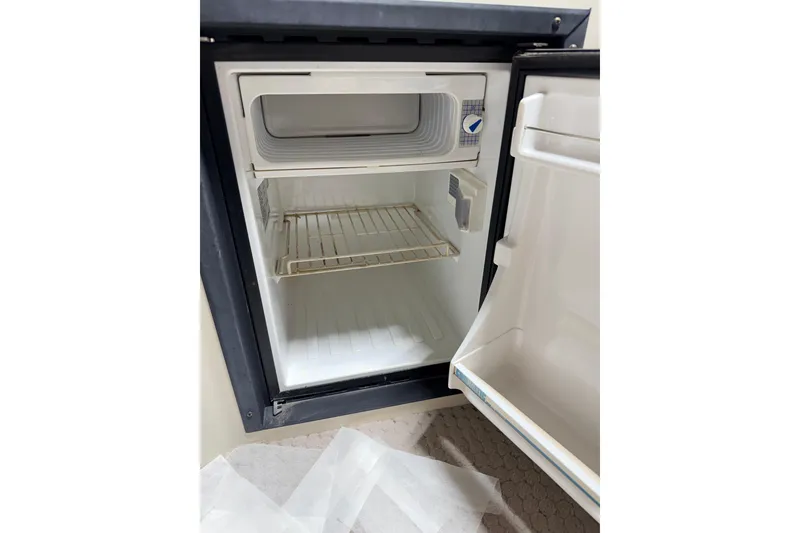 Slide: The Image of Open refrigerator inside a 2004 Bennington 2875RLX boat, showing empty shelves. - 22