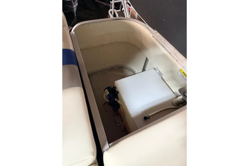 Slide: The Image of Storage compartment of a 2004 Bennington 2875RLX boat, featuring a white tank and pump. - 27