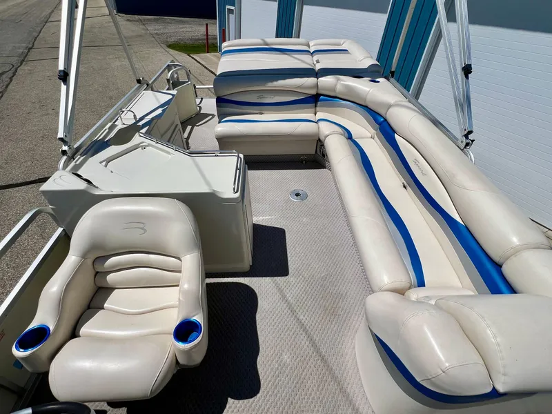 Slide: The Image of 2004 Bennington 2875RLX boat interior with white and blue seating, steering console, and cup holders. - 9