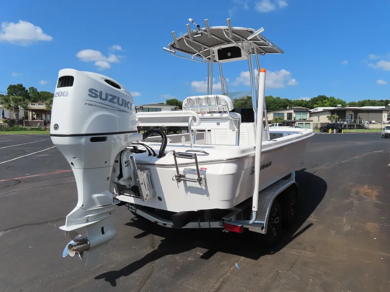 Slide: The Image of 2025 Savannah 220 IS boat with Suzuki engine on trailer, parked outdoors. - 4