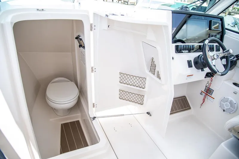 Slide: The Image of 2026 Sailfish 276 DC boat interior with helm and compact marine toilet. - 6
