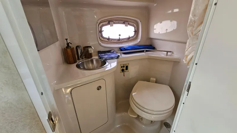 Slide: The Image of 2013 Sea Ray 280 Sundancer bathroom with sink, toilet, and porthole window. - 25