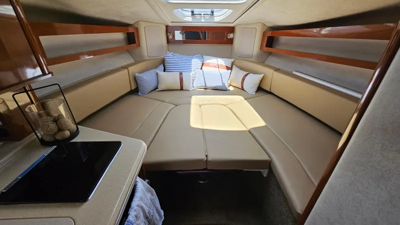 Slide: The Image of 2013 Sea Ray 280 Sundancer cabin interior with beige seating and decorative pillows. - 27