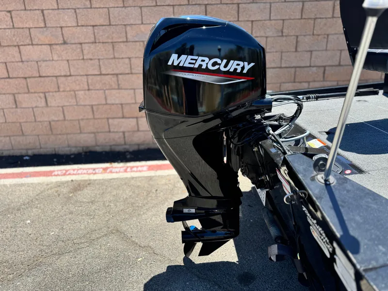 Slide: The Image of 2021 Tracker Pro Team 175 TXW with Mercury outboard motor, parked on pavement. - 10