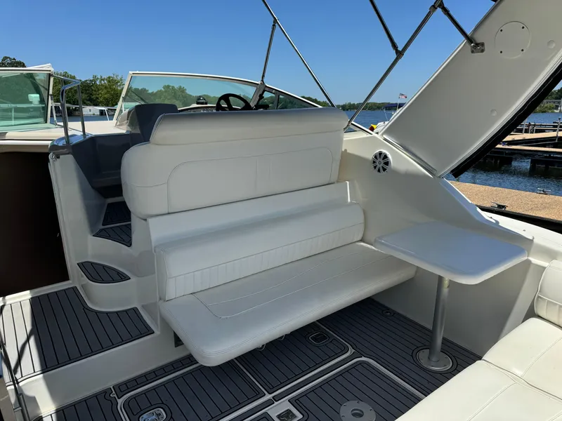 Slide: The Image of 2004 Cruisers Yachts 320 Express interior with white seating and table, dockside view. - 14