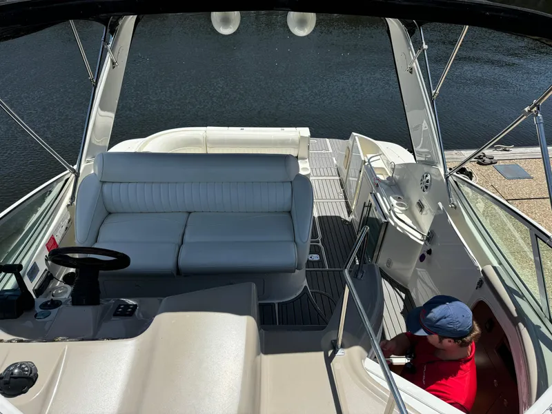 Slide: The Image of 2004 Cruisers Yachts 320 Express interior with seating and helm, docked by the water. - 22
