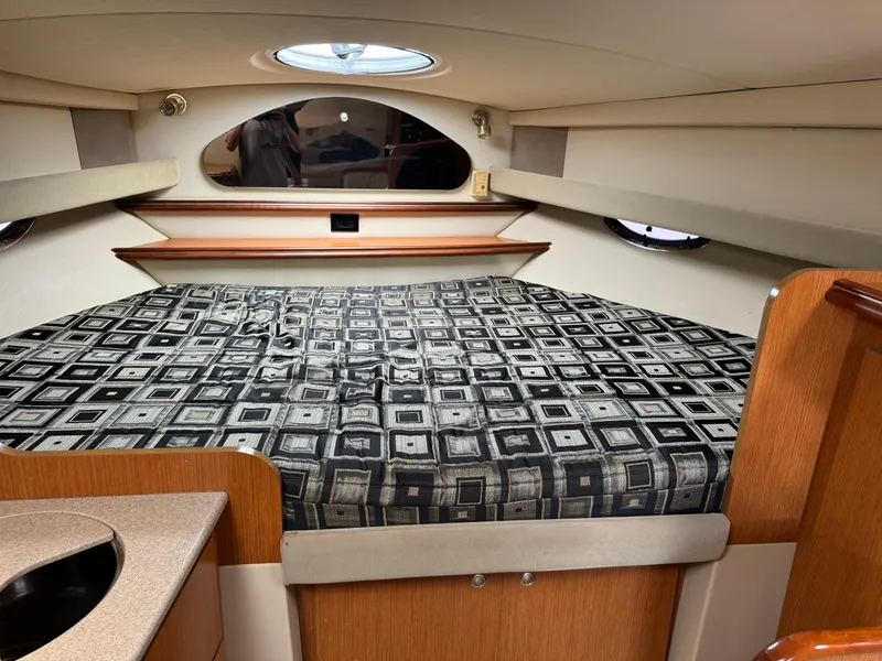 Slide: The Image of 2004 Cruisers Yachts 320 Express cabin interior with patterned bedding and wood accents. - 26