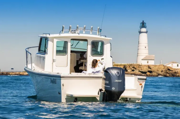 Slide: The Image of 2025 Parker 2520 XLD Sport Cabin boat near lighthouse on calm sea. - 2