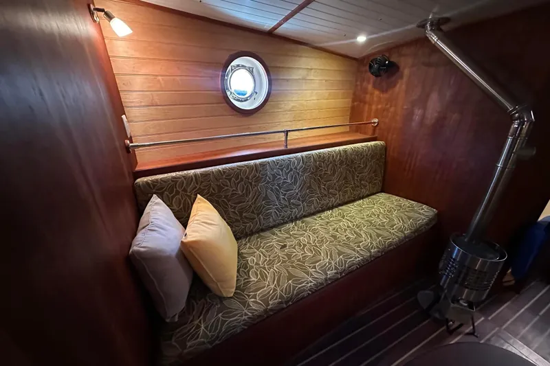 Slide: The Image of Cozy interior of 2012 Custom Steel Trawler with cushioned seating and porthole window. - 38