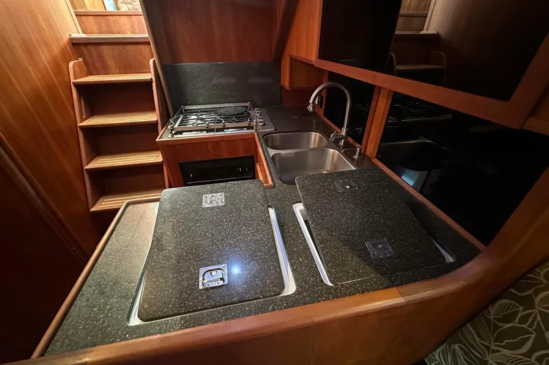 Slide: The Image of Compact kitchen in a 2012 Custom Steel Trawler with stove, sink, and wooden cabinetry. - 43