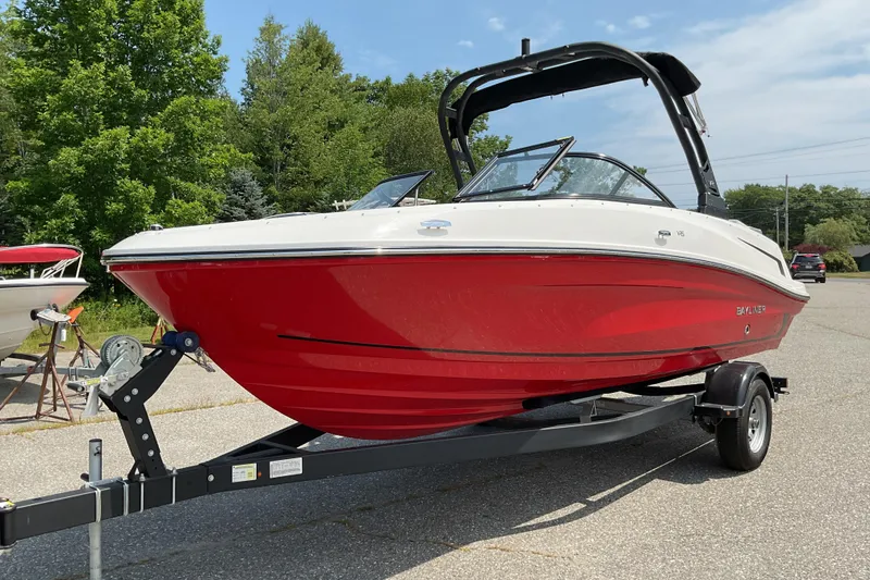 Slide: The Image of 2025 Bayliner VR5 OB boat with red hull on a trailer, parked outdoors. - 4