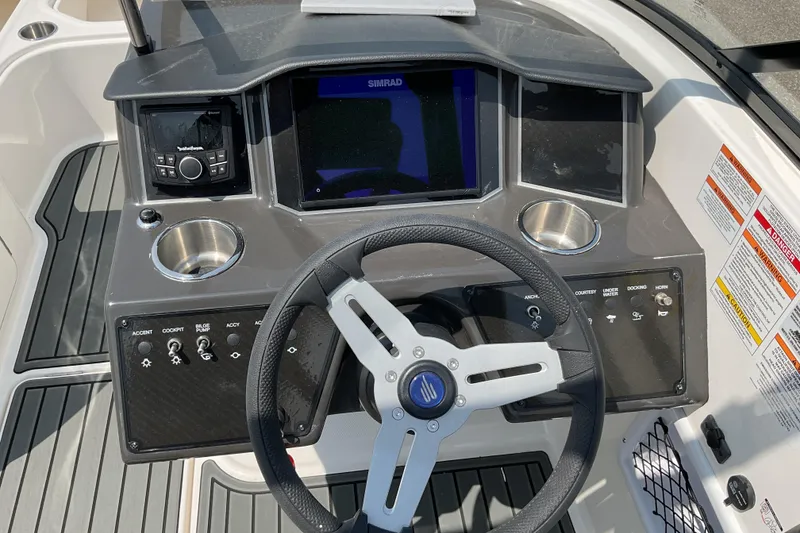 Slide: The Image of 2025 Bayliner VR5 OB boat dashboard with steering wheel, controls, and cup holders. - 9