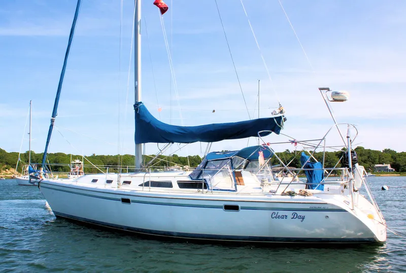 Slide: The Image of 1998 Catalina 42 MkII sailboat on water, blue cover, clear sky, scenic background. - 13