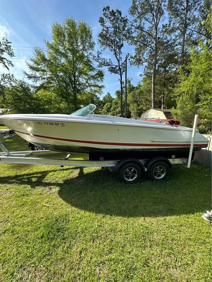 Slide: The Image of 2001 Chris-Craft Launch 22 boat on trailer, parked on grass, surrounded by trees. - 2
