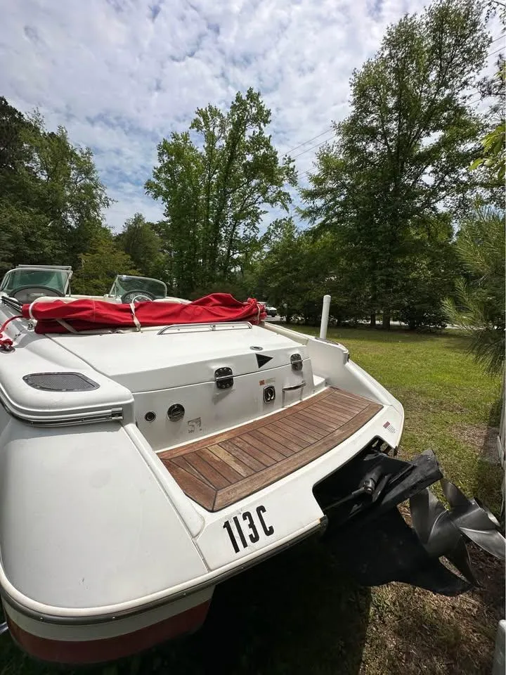 Slide: The Image of 2001 Chris-Craft Launch 22 boat with red cover, parked on grassy area, surrounded by trees. - 8