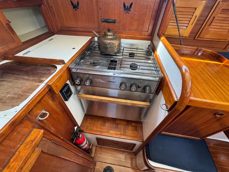 Slide: The Image of 1970 Cheoy Lee Luders 36 yacht kitchen with stove, kettle, and wooden cabinetry. - 15