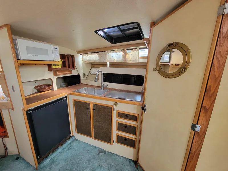Slide: The Image of 1979 Bayliner 3250 boat interior with seating and windshield, docked outdoors. - 11