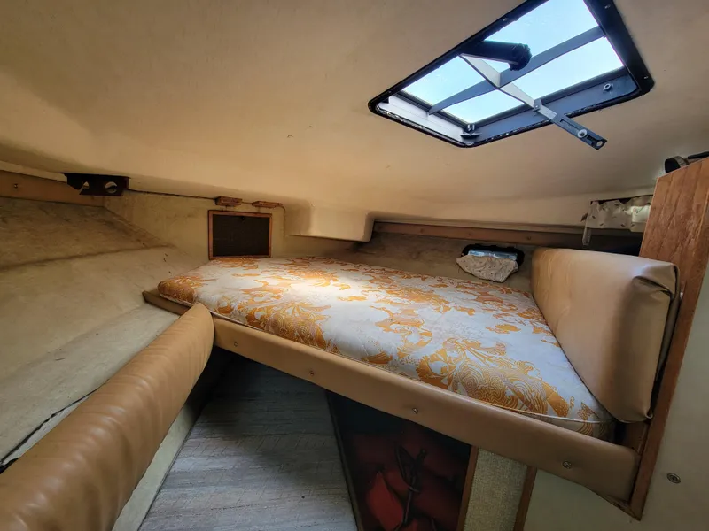 Slide: The Image of 1979 Bayliner 3250 cabin interior with a cozy bed and overhead hatch. - 18