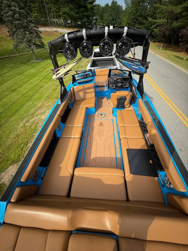 Slide: The Image of 2022 Axis T250 boat interior with tan seating and blue accents, featuring wakeboard tower speakers. - 12