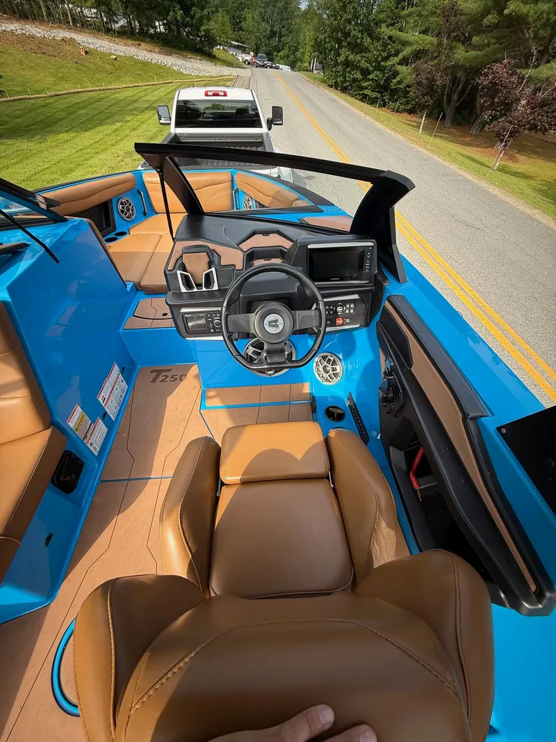 Slide: The Image of 2022 Axis T250 boat interior with blue and tan design, parked on a road. - 13