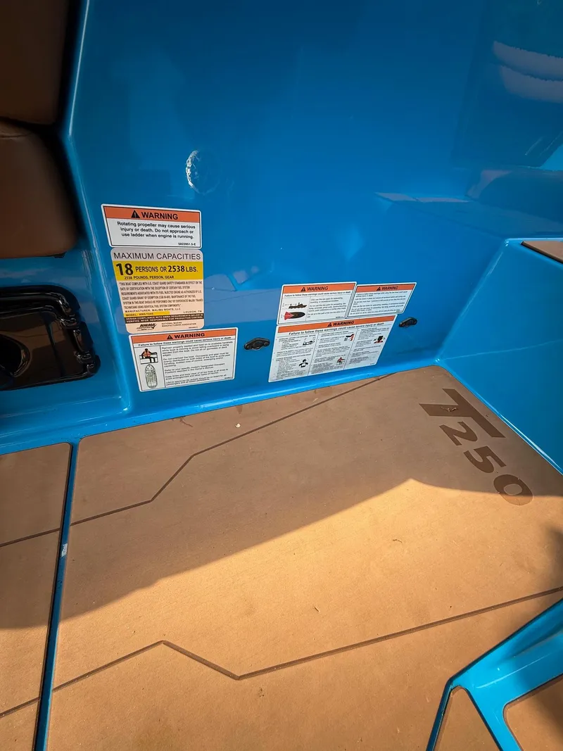 Slide: The Image of 2022 Axis T250 boat interior with capacity warning labels and blue flooring. - 14