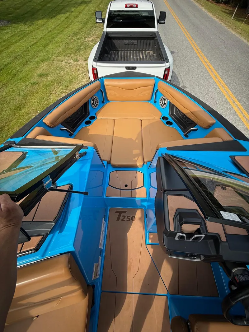 Slide: The Image of 2022 Axis T250 boat interior with tan seats, blue accents, and a white truck in view. - 15