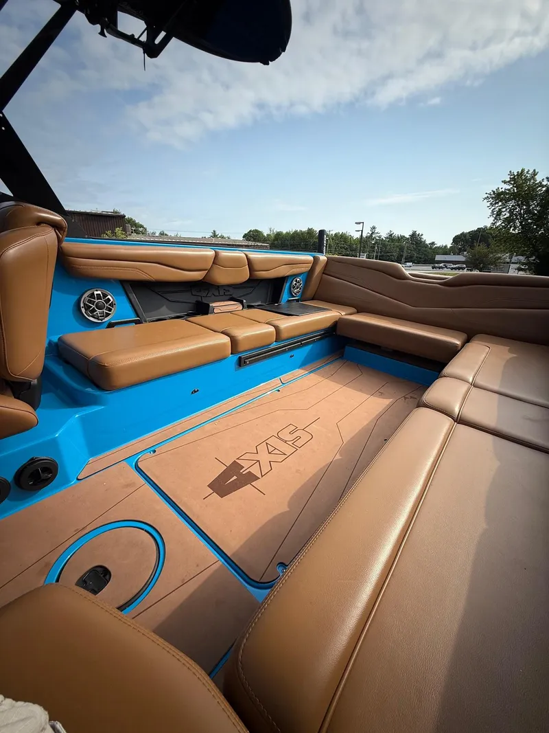 Slide: The Image of 2022 Axis T250 boat interior with tan leather seats and blue accents under a clear sky. - 16