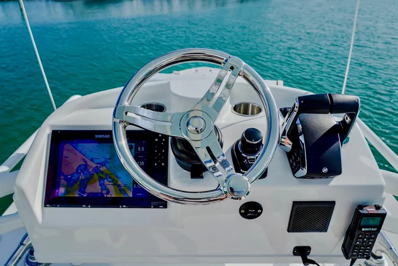 Slide: The Image of 2023 Yellowfin 42 boat helm with steering wheel, navigation screen, and controls on open water. - 19