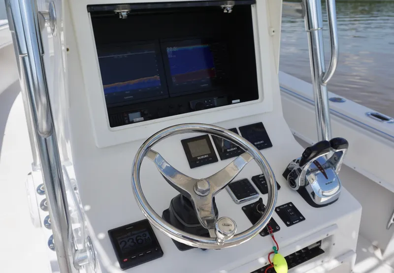 Slide: The Image of 2003 Contender 31 Open boat helm with steering wheel, dual displays, and control panel. - 16