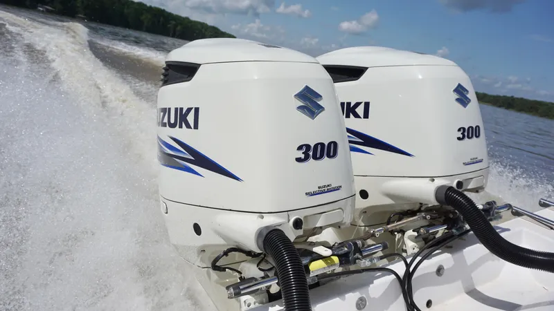 Slide: The Image of Twin Suzuki 300 outboard engines powering a 2003 Contender 31 Open boat on a lake. - 22