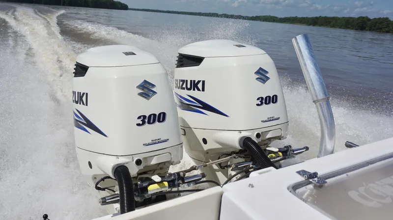 Slide: The Image of Twin Suzuki 300 outboard engines powering a 2003 Contender 31 Open boat on a lake. - 23