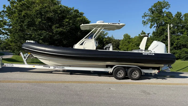 Slide: The Image of 2022 Brig Eagle 8 boat on trailer, parked on a sunny road with trees in background. - 2