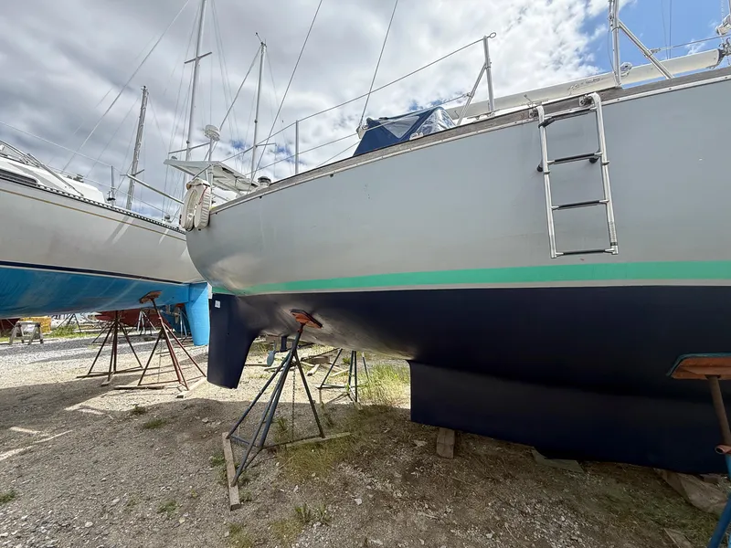 Slide: The Image of 1982 Tartan 37 sailboat on stands, under cloudy sky, with visible ladder and keel. - 1