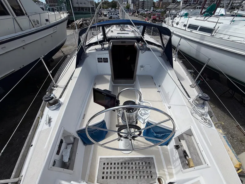 Slide: The Image of 1982 Tartan 37 sailboat cockpit with steering wheel, docked among other boats. - 21