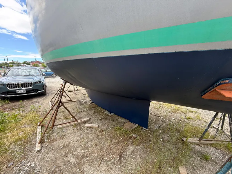 Slide: The Image of 1982 Tartan 37 sailboat hull on stands, parked beside a car. - 3