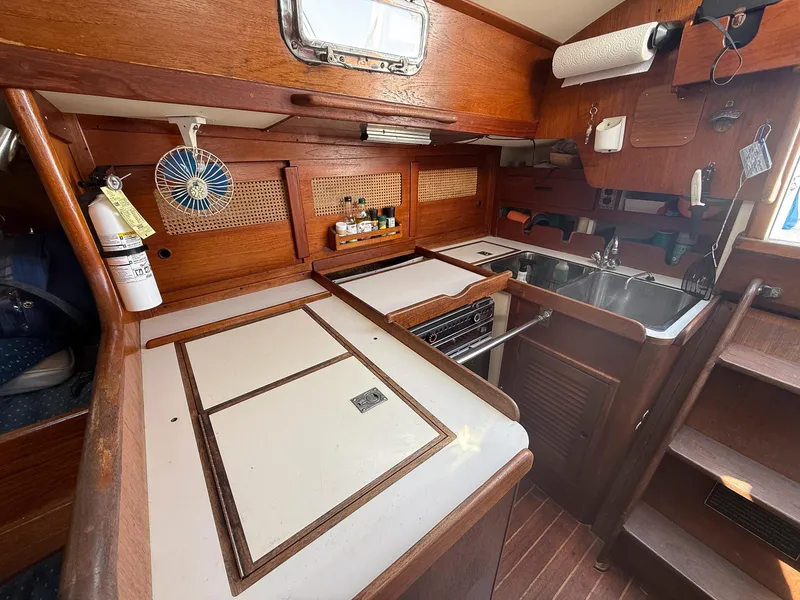 Slide: The Image of 1982 Tartan 37 yacht kitchen with wooden cabinetry, sink, stove, and fan. - 45
