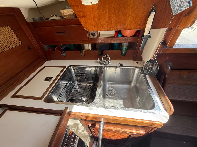 Slide: The Image of Galley sink in 1982 Tartan 37 sailboat with wooden cabinetry and storage shelves. - 47