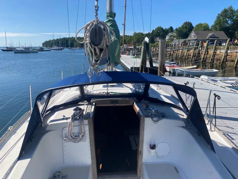 Slide: The Image of 1982 Tartan 37 sailboat docked at a marina, featuring a blue canopy and scenic waterfront. - 5