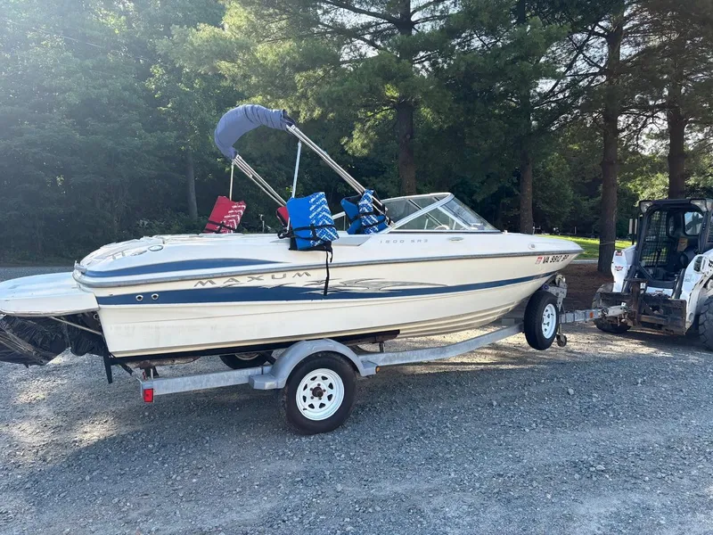 The Image of 2006 Maxum 1800 SR3 boat on trailer, parked on gravel, surrounded by trees. - 0