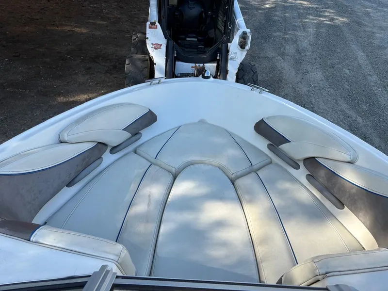 Slide: The Image of 2006 Maxum 1800 SR3 boat interior with white cushioned seating, parked on gravel. - 5