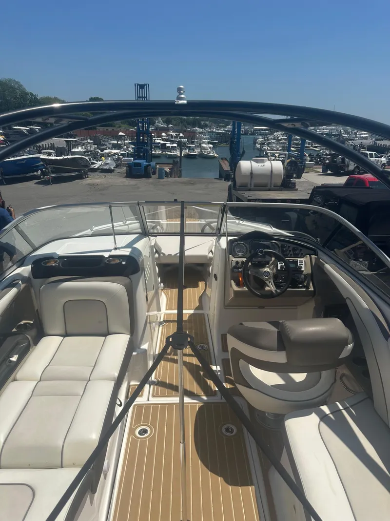 Slide: The Image of 2013 Yamaha Boats 242 Limited S interior at marina, showcasing seating and controls. - 13