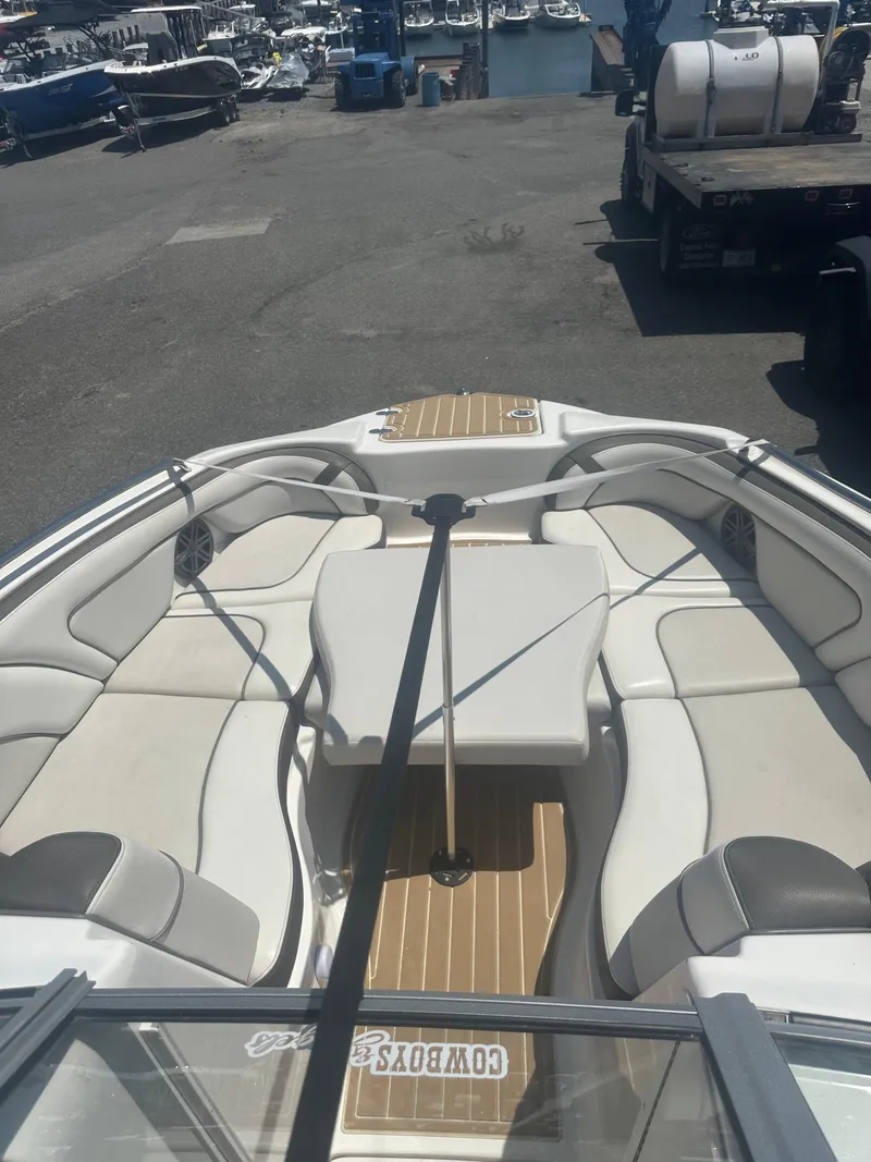 Slide: The Image of 2013 Yamaha Boats 242 Limited S interior with seating and table, docked at marina. - 14