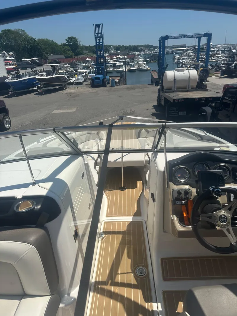 Slide: The Image of 2013 Yamaha Boats 242 Limited S interior view at marina, showcasing dashboard and seating. - 6