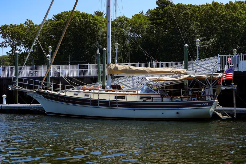 The Image of 1987 Gozzard 36 sailboat docked, featuring classic design and American flag. - 0