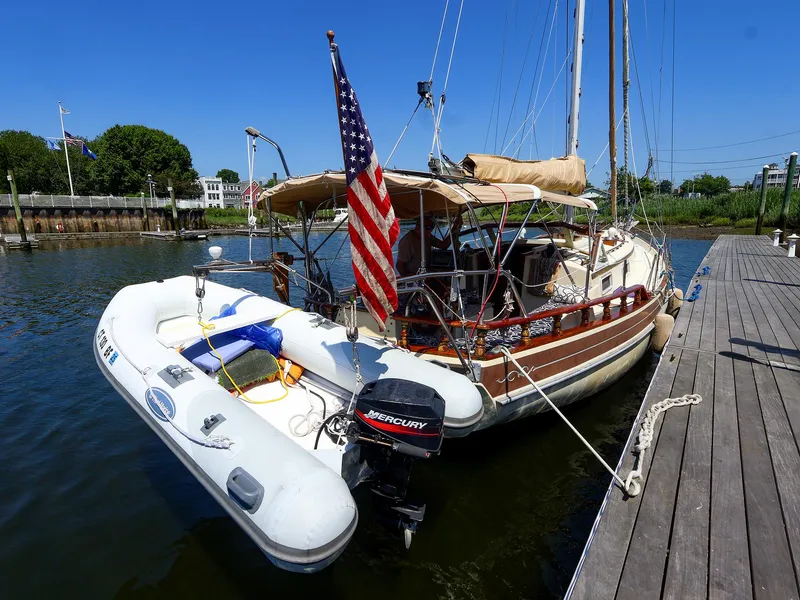 Slide: The Image of 1987 Gozzard 36 sailboat docked with inflatable dinghy and American flag. - 28