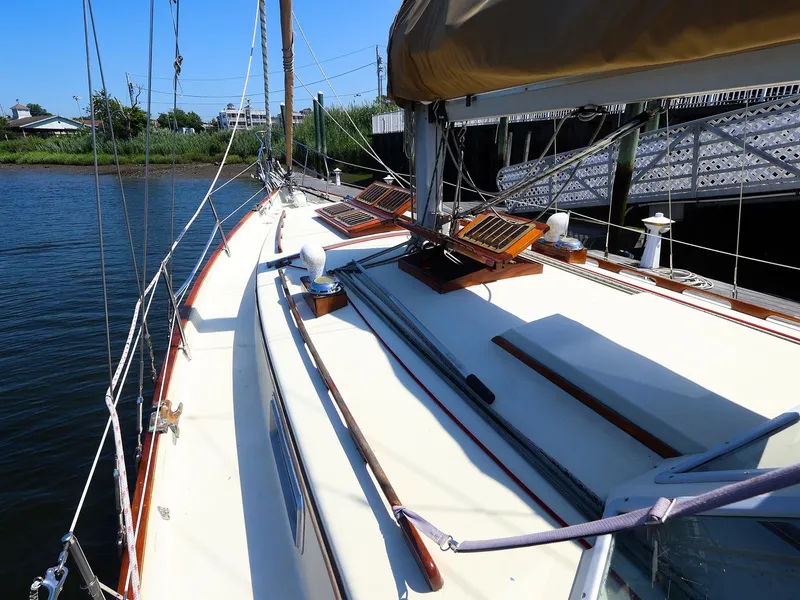Slide: The Image of 1987 Gozzard 36 sailboat deck with wooden accents, docked by calm waters. - 3