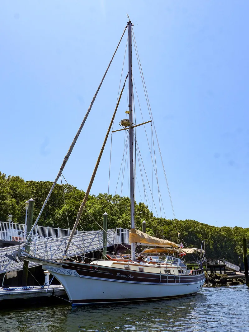 Slide: The Image of 1987 Gozzard 36 sailboat docked at a marina under clear blue sky. - 30