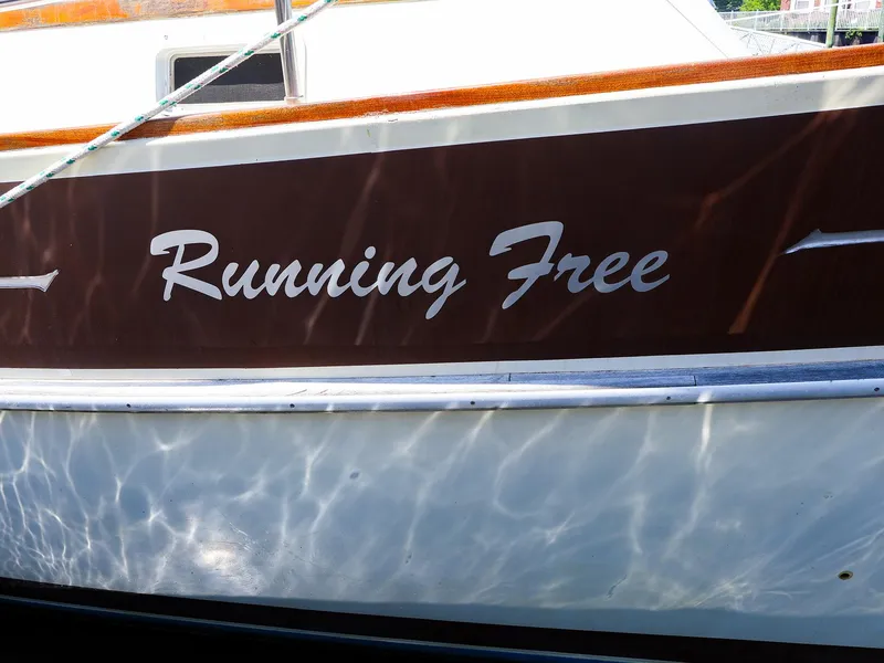 Slide: The Image of 1987 Gozzard 36 sailboat named "Running Free" with water reflections on the hull. - 34